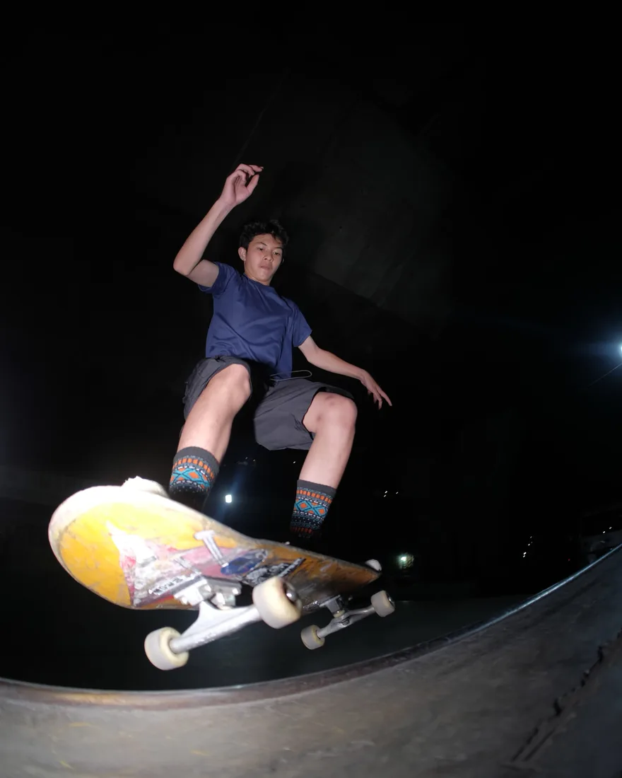 Ael floating over the park’s transition on a night session, board right in front of the lens.